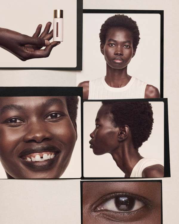 Cosmetic product is held by a hand near framed photos of a dark-skinned woman's face, with close-ups of a smile and eye.