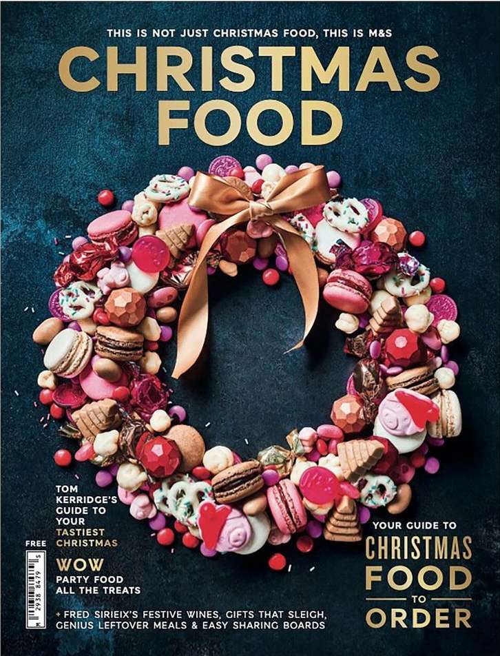 Christmas food wreath made of cookies and candy, tied with a gold ribbon, against a dark blue background for a magazine cover.