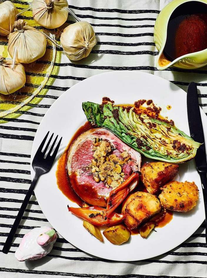 Overhead shot of a plated meat entree with cabbage, potatoes, and sauce, set on a striped tablecloth next to a gravy boat.