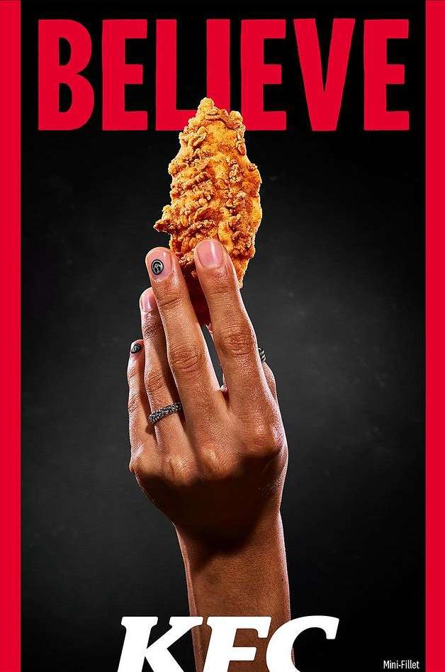 Close-up of a hand holding a fried chicken fillet against a dark background with the text 'BELIEVE' and the KFC logo.