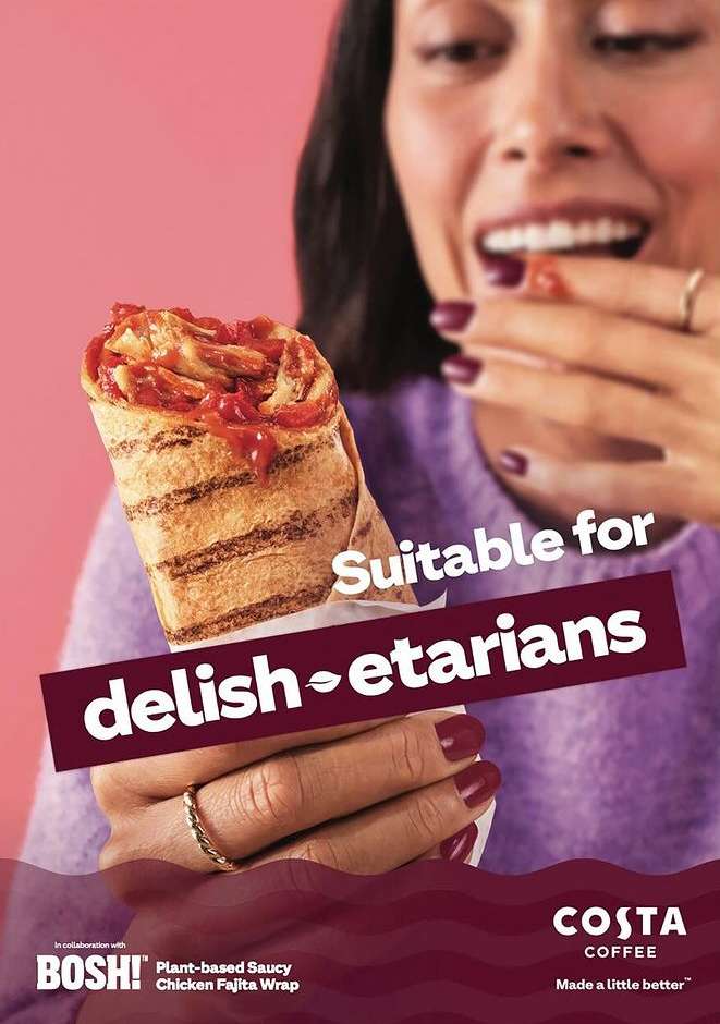 A woman smiles while holding a plant-based chicken fajita wrap in front of a pink background for a Costa Coffee ad campaign.