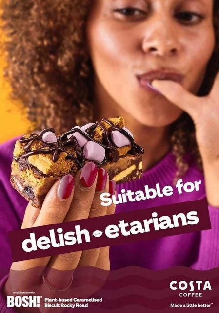 A woman holds a chocolate-covered caramel biscuit with marshmallows on top with text about being suitable for vegetarians.