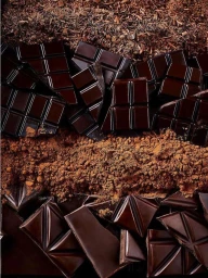 Overhead shot of dark chocolate bars, broken shards, cocoa powder and chocolate shavings layered vertically