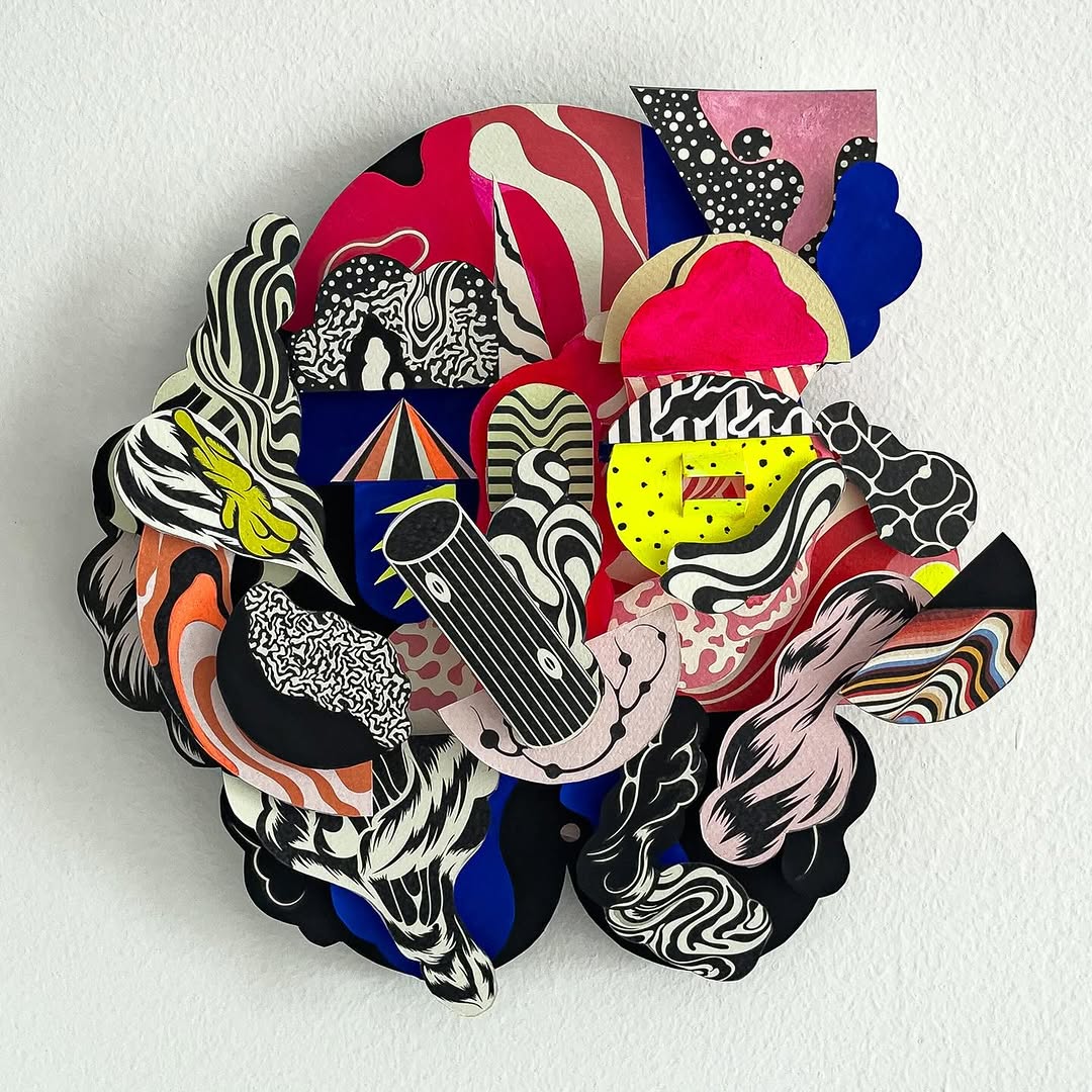 Abstract paper collage featuring red, blue, yellow, black, and white shapes with patterns and textures, mounted on a white background.