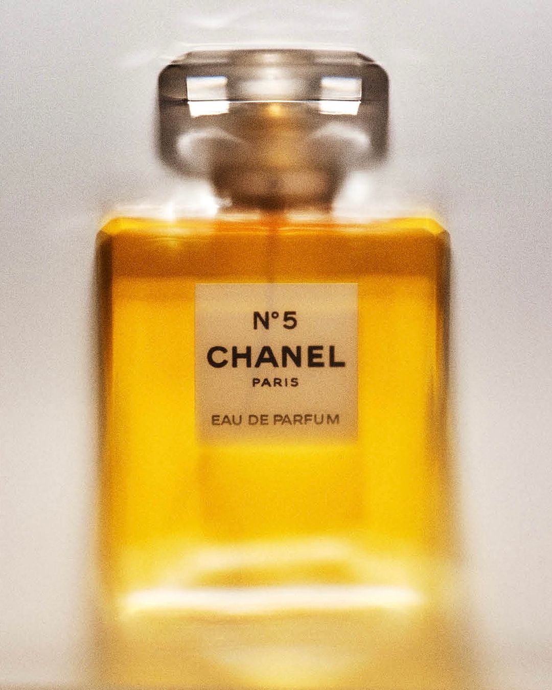 Close-up studio shot of Chanel N°5 Eau de Parfum bottle, showcasing its golden liquid, transparent glass, and minimalist label design.