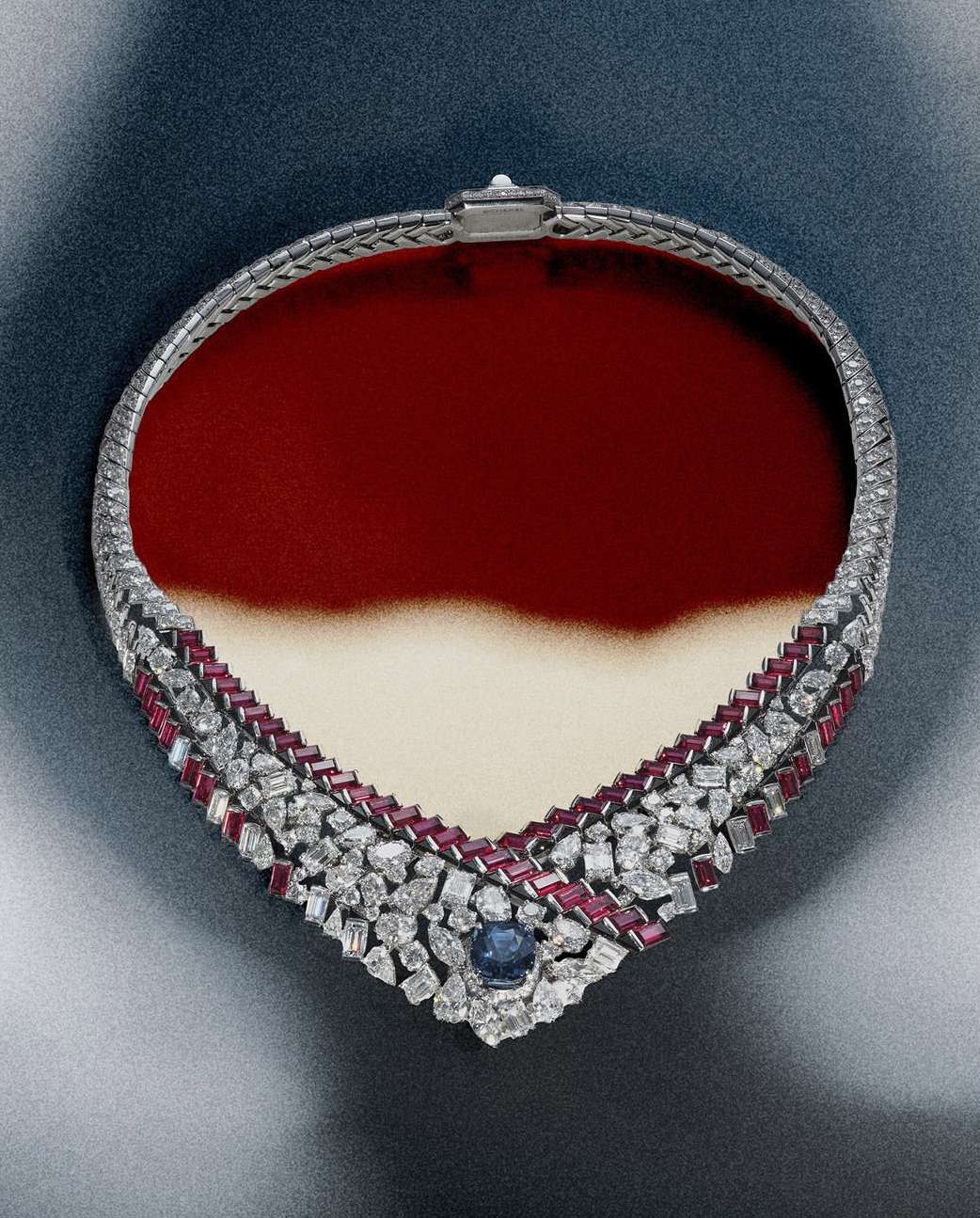 Elegant diamond and ruby necklace on a red and white gradient background, close-up studio shot highlighting the intricate details and vibrant colors.