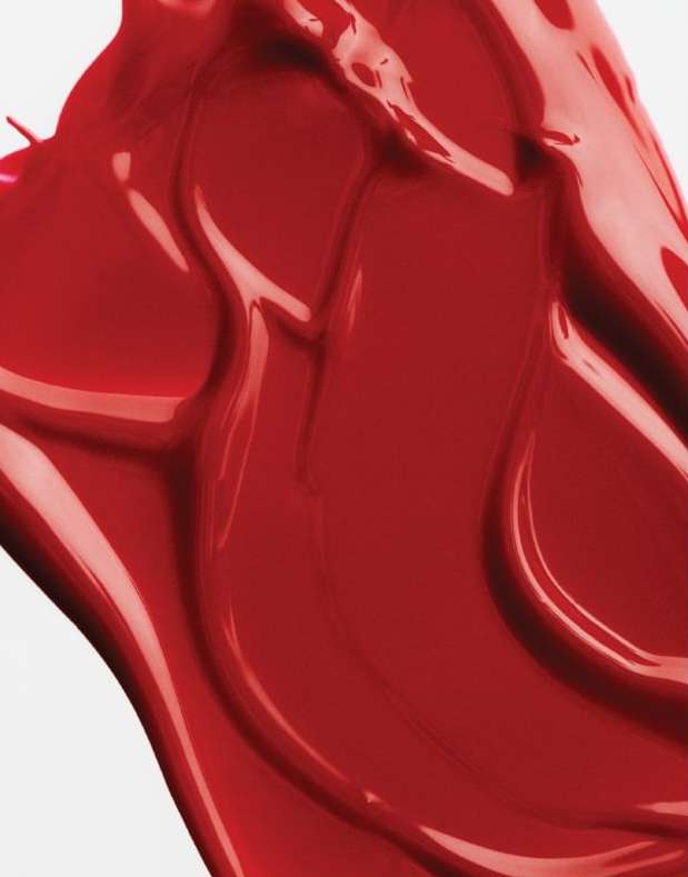 Close-up abstract photograph of textured red liquid against a white backdrop. The red substance appears glossy and viscous.