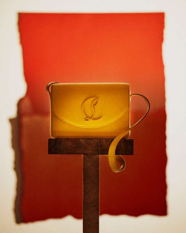 Yellow leather purse on a brown wooden pedestal against an abstract red and white background, product shot, luxury fashion accessory.
