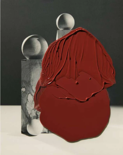Abstract still life featuring a red paint-like form contrasted with geometric gray shapes and spheres against a dark gray background.