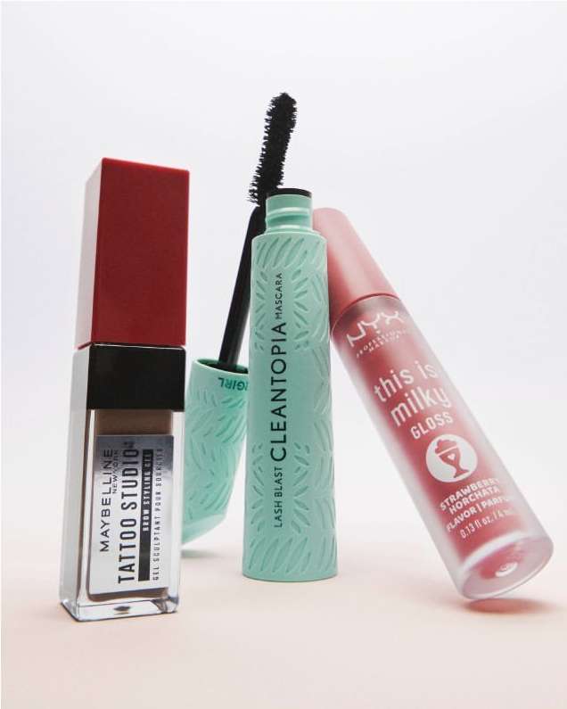 Assorted makeup products including lip gloss and mascara from Maybelline and NYX set against a clean, white backdrop. Beauty product shot.