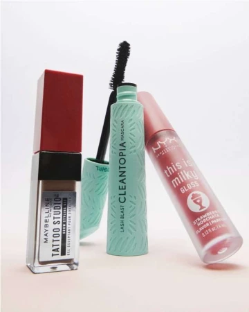 Assorted makeup products including lip gloss and mascara from Maybelline and NYX set against a clean, white backdrop. Beauty product shot.