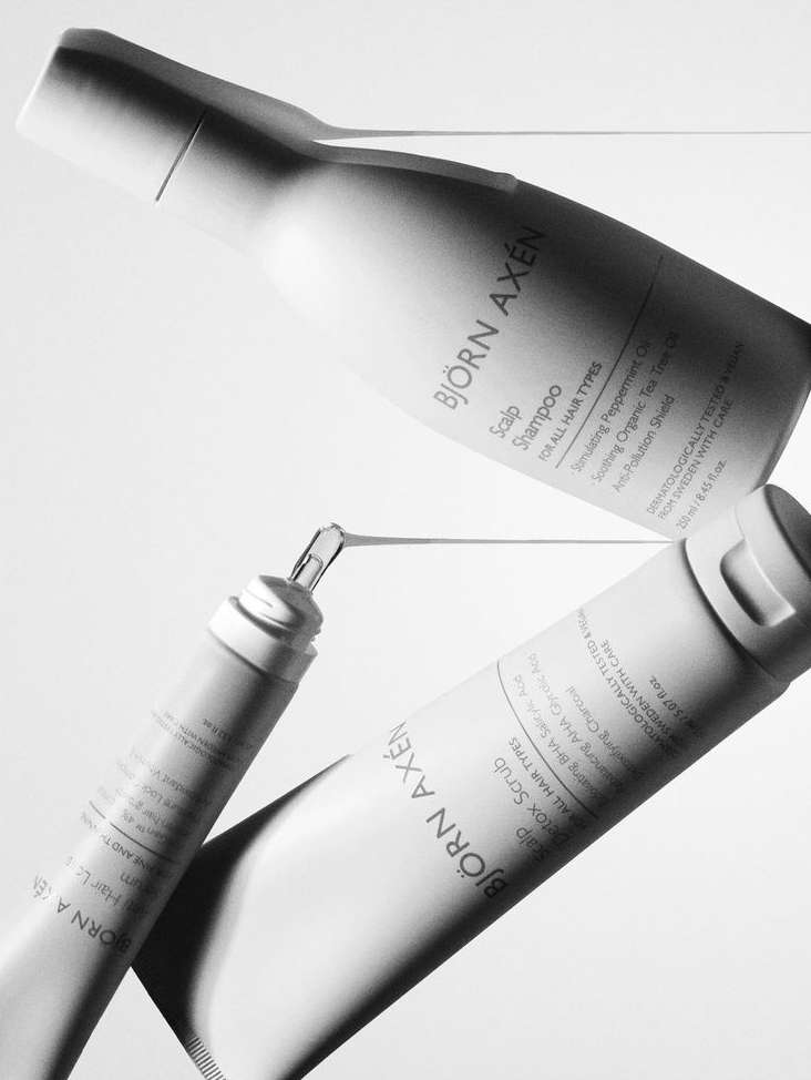 Björn Axén product line featuring shampoo, scrub, and hair care products are displayed against a bright, neutral background in a studio setting.