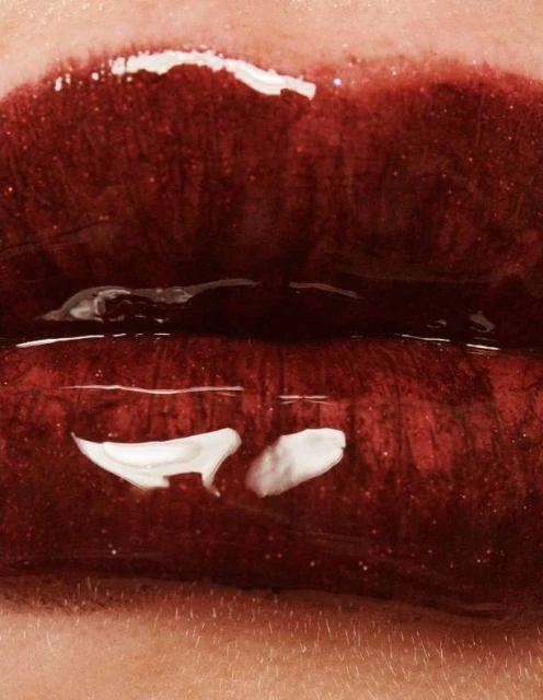 Close-up shot of open red lips with glossy lipstick and visible skin texture around the mouth in a vertical, macro studio shot.