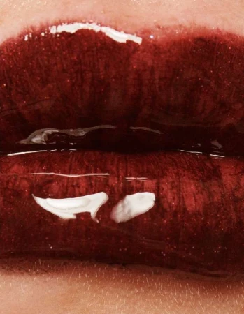 Close-up shot of open red lips with glossy lipstick and visible skin texture around the mouth in a vertical, macro studio shot.