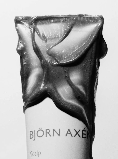 Close-up of a Bjorn Axen scalp treatment tube with product oozing from the top, set against a clean white background.