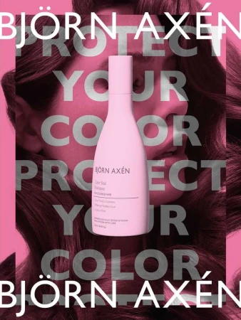 Bjorn Axen haircare product bottle, pale pink color, shown against a background of a woman with long wavy brown hair.