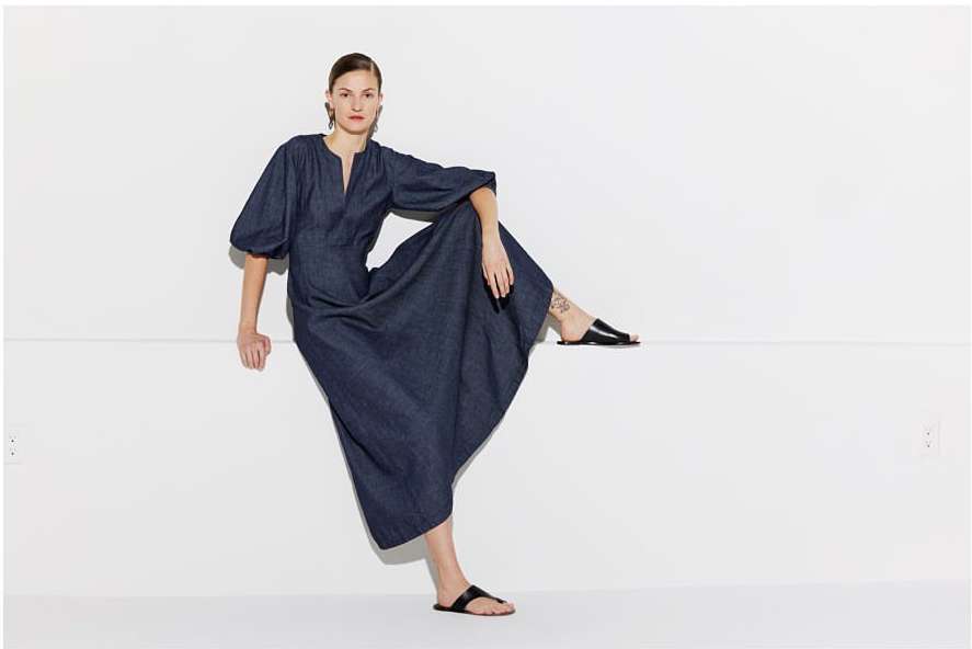 Model in dark blue dress with balloon sleeves seated against a white background by Masato Onoda