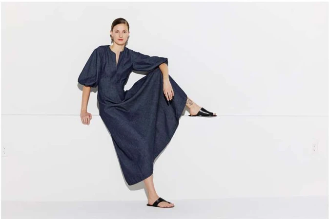 Model in dark blue dress with balloon sleeves seated against a white background by Masato Onoda