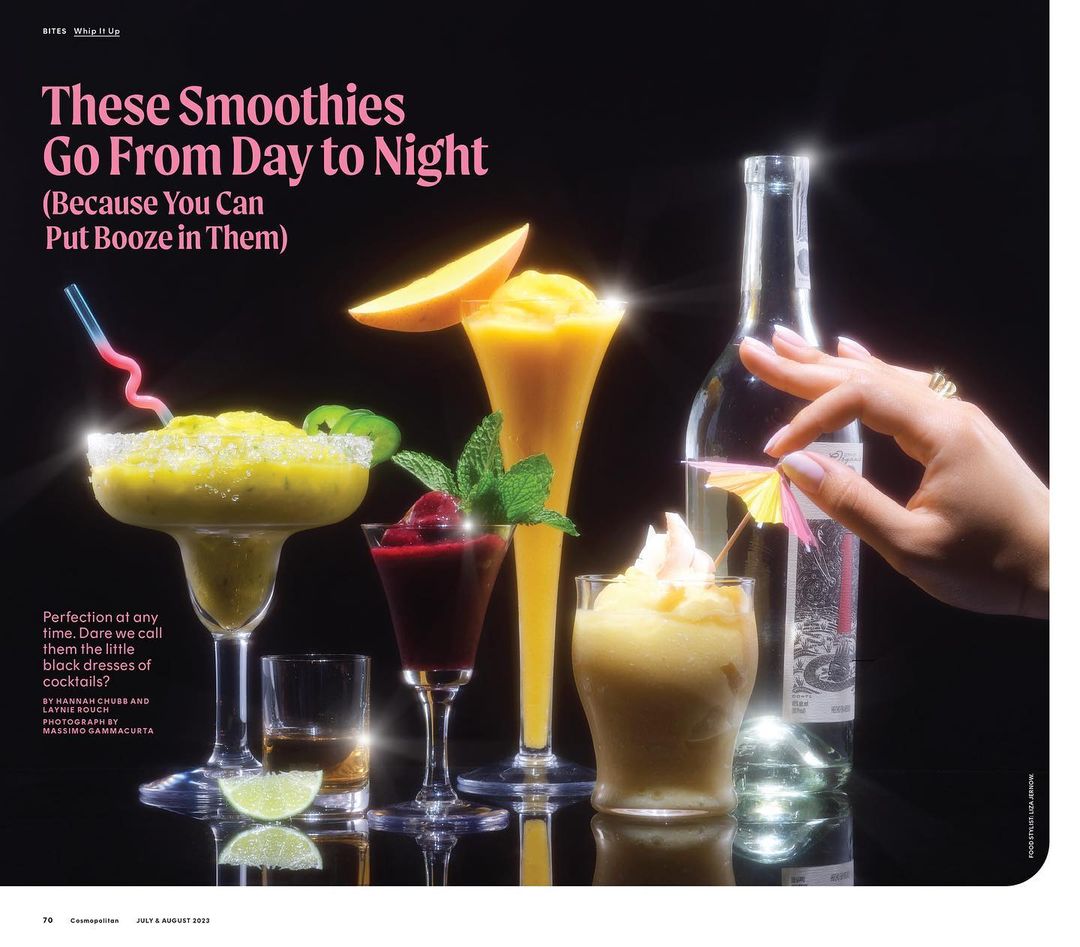 Colorful smoothies in cocktail glasses, featuring mango, berries, and pineapple with decorative umbrellas and mint on a reflective surface.