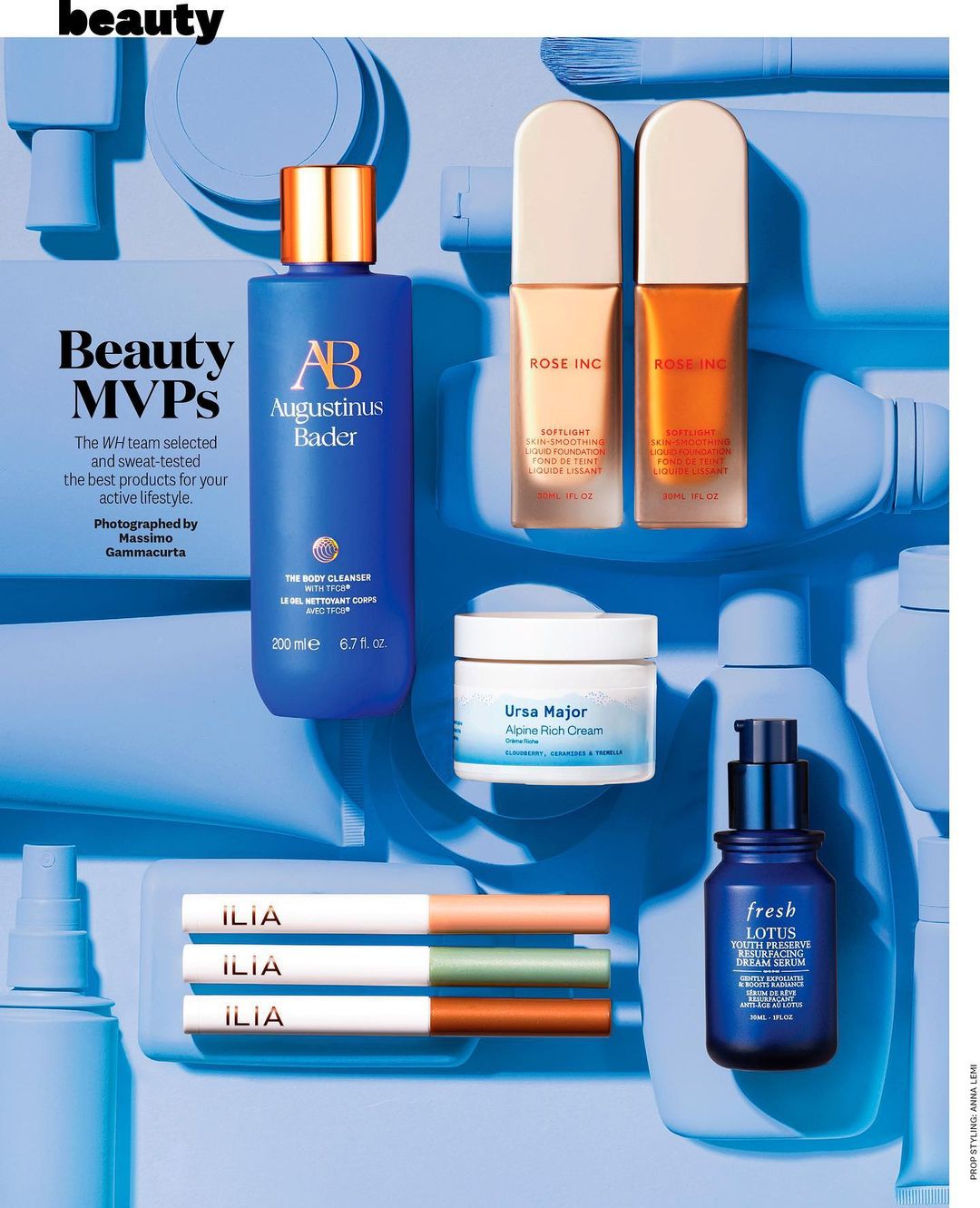 Beauty product flat lay. Variety of skincare and cosmetic containers in blue and gold tones on a blue background with soft lighting.