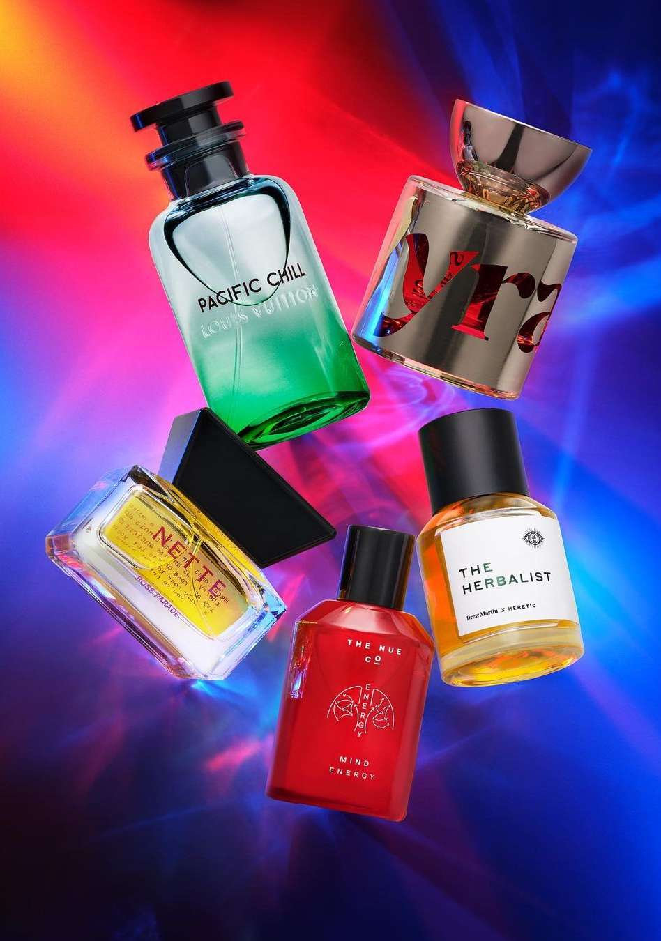 Still life shot of assorted perfume bottles, including brands like Louis Vuitton and The Herbalist, set against a vibrant, dynamic backdrop.