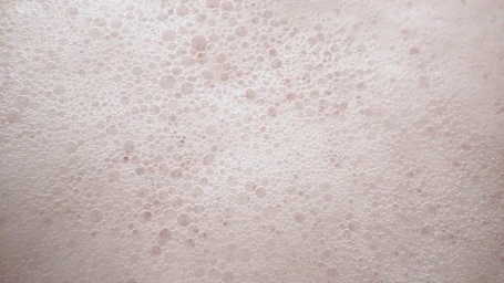 Close-up macro view of soap suds and tiny bubbles creating a dense, textured foam surface.