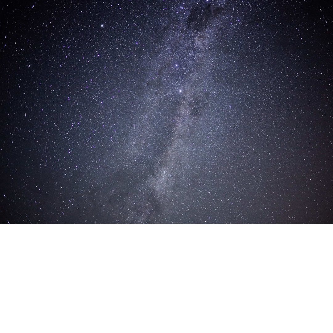 Vibrant night sky landscape featuring the Milky Way galaxy with a dense field of stars against a dark blue atmosphere.