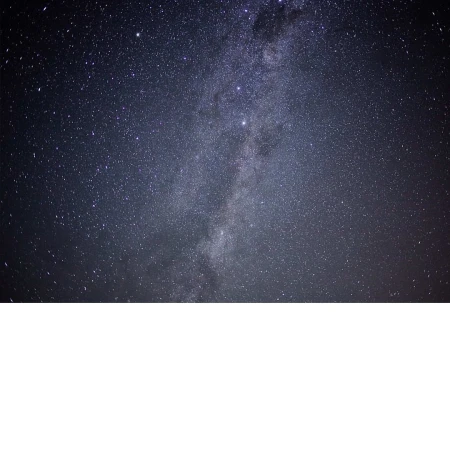 Vibrant night sky landscape featuring the Milky Way galaxy with a dense field of stars against a dark blue atmosphere.