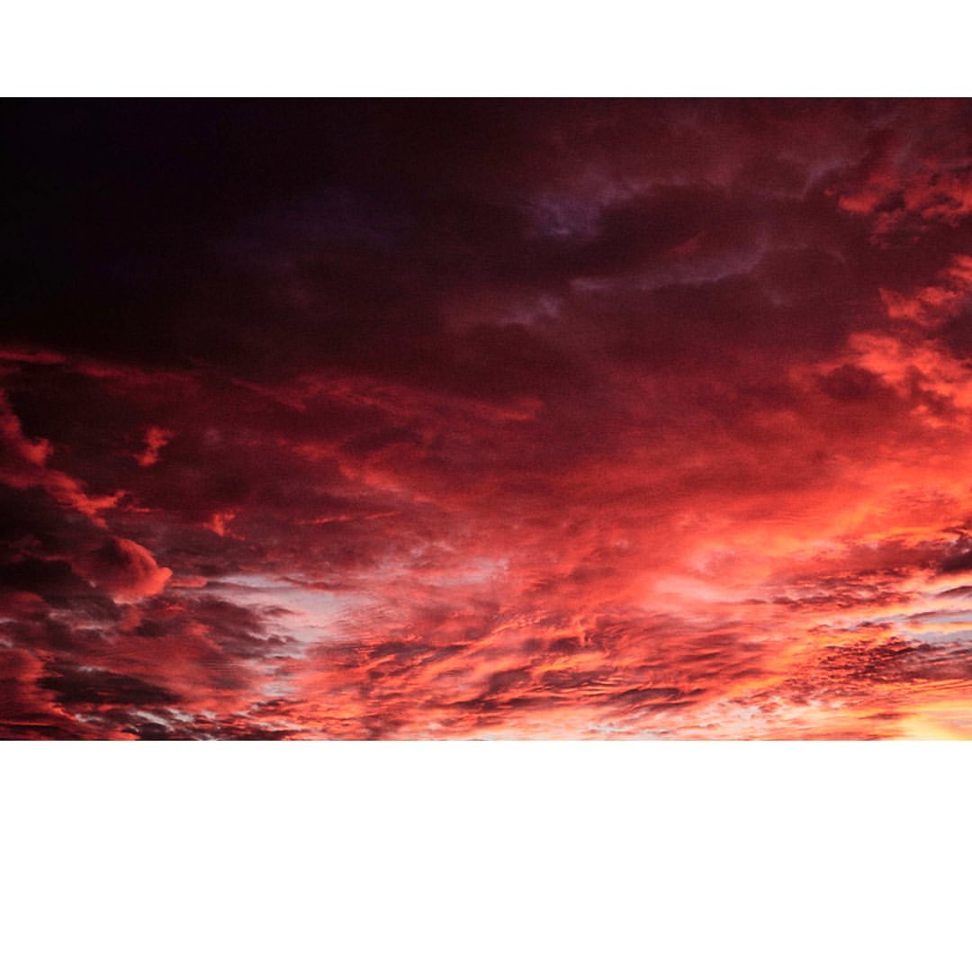 Dramatic sky with vibrant red, orange, and black storm clouds filling the frame, creating an intense and moody skyscape at dusk.