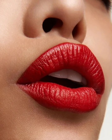 Extreme close-up of lips wearing vibrant red lipstick with teeth slightly showing
