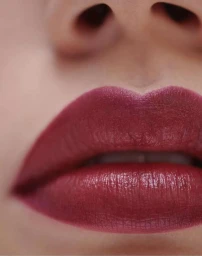 Extreme close-up macro portrait of dark red glossy lipstick on lips by photographer Mateusz Sitek