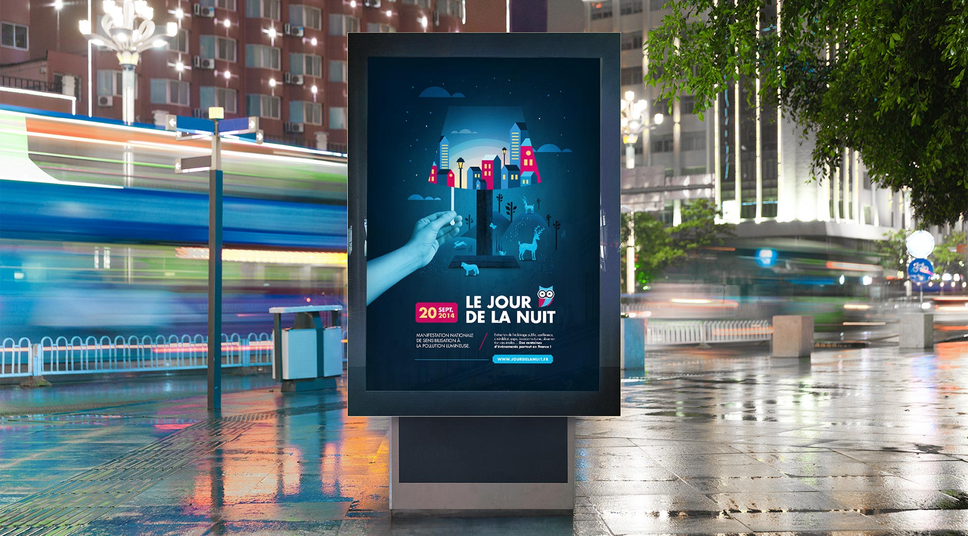 City street at night with a backlit poster of an illustration featuring a hand, city, and animals under a stylized lamp.