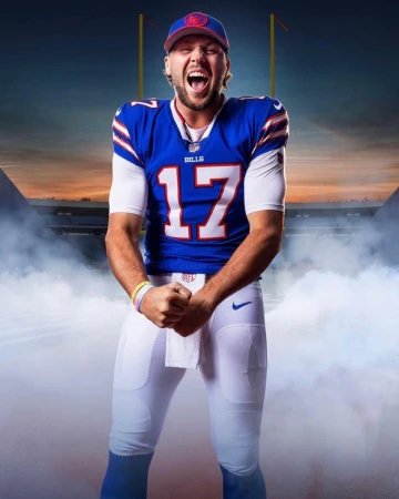 Football player in uniform with stadium in the background. Man in blue jersey and white pants yells with his fists clenched.