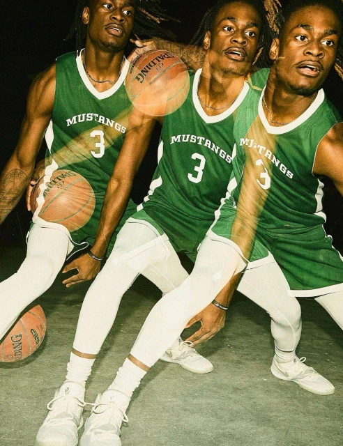 Multiple exposure shot of a young African-American basketball player dribbling a Spalding ball while wearing a green Mustangs jersey.