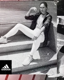 Black and white editorial portrait of a woman seated on stone steps wearing sportswear and sneakers.