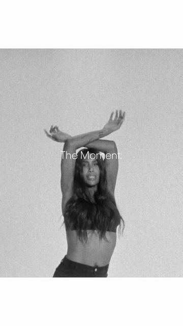 Monochrome portrait of a woman with dark hair crossing her arms overhead against a textured background