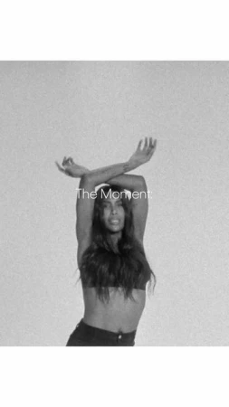Monochrome portrait of a woman with dark hair crossing her arms overhead against a textured background