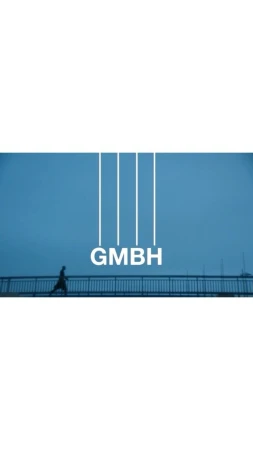 Person walking on a bridge under a blue sky with 'GMBH' text. Minimalist style with a distant horizon, creating a sense of scale.