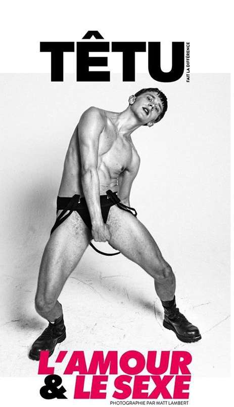 Black and white image features a shirtless male model in black bottoms against a white backdrop, showcasing fashion and entertainment.