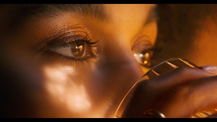 Macro portrait of a woman drinking from a crystal glass under warm golden light by photographer Matt Lambert.