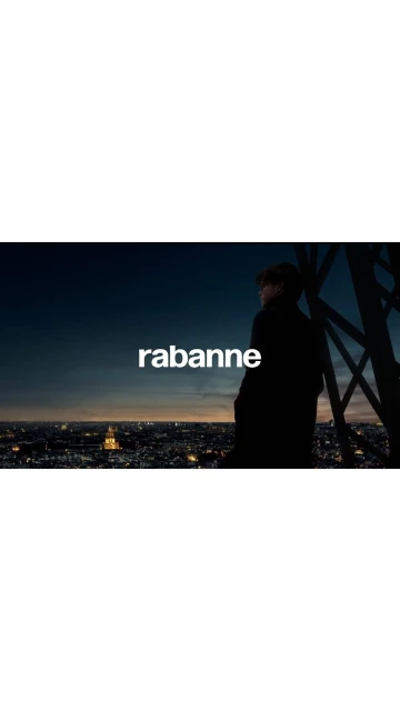 A man in silhouette overlooks a cityscape at night, standing near the Eiffel Tower, with the logo "rabanne" displayed.