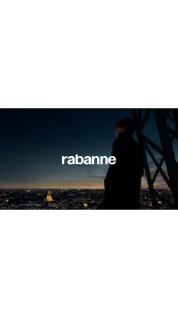 A man in silhouette overlooks a cityscape at night, standing near the Eiffel Tower, with the logo "rabanne" displayed.