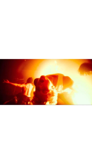 Person in a dimly lit space with a strong backlight. Red and orange tones create a dramatic effect, showcasing silhouettes.