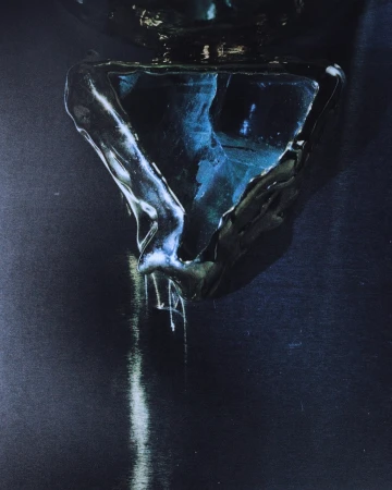 Abstract still life of a reflective, dark triangular object with liquid, creating depth and highlights in a dark blue and black color palette.