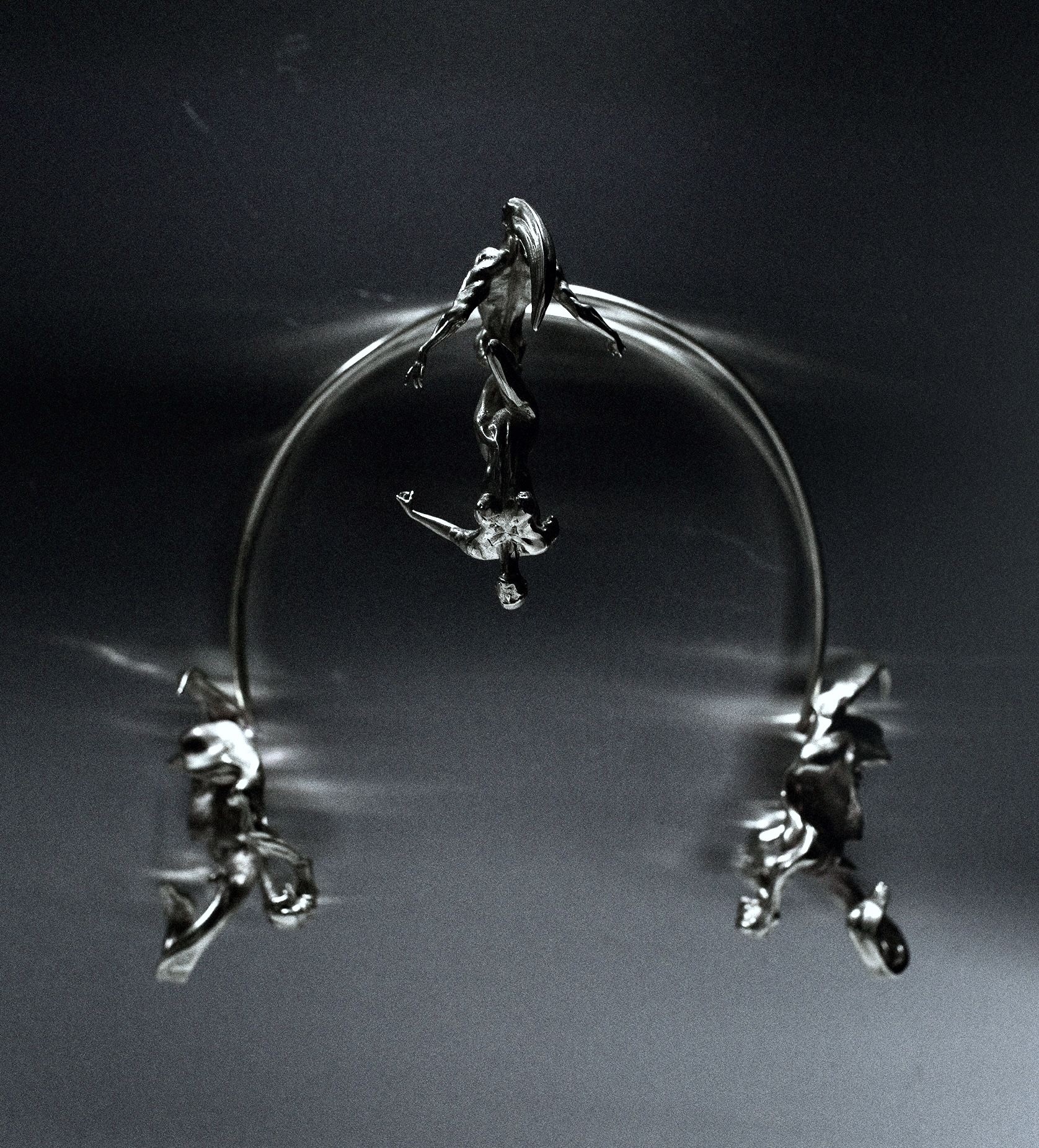 Abstract metallic sculpture featuring stylized human figures connected by an arc, set against a dark gradient background.
