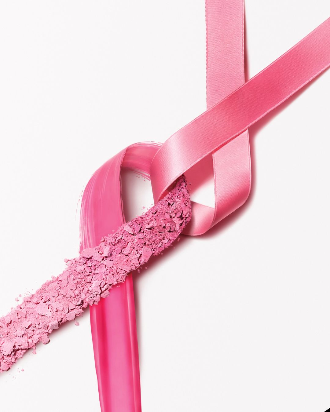 Pink ribbon and crushed powder makeup for breast cancer awareness on white background. Beauty, health, and support concept.
