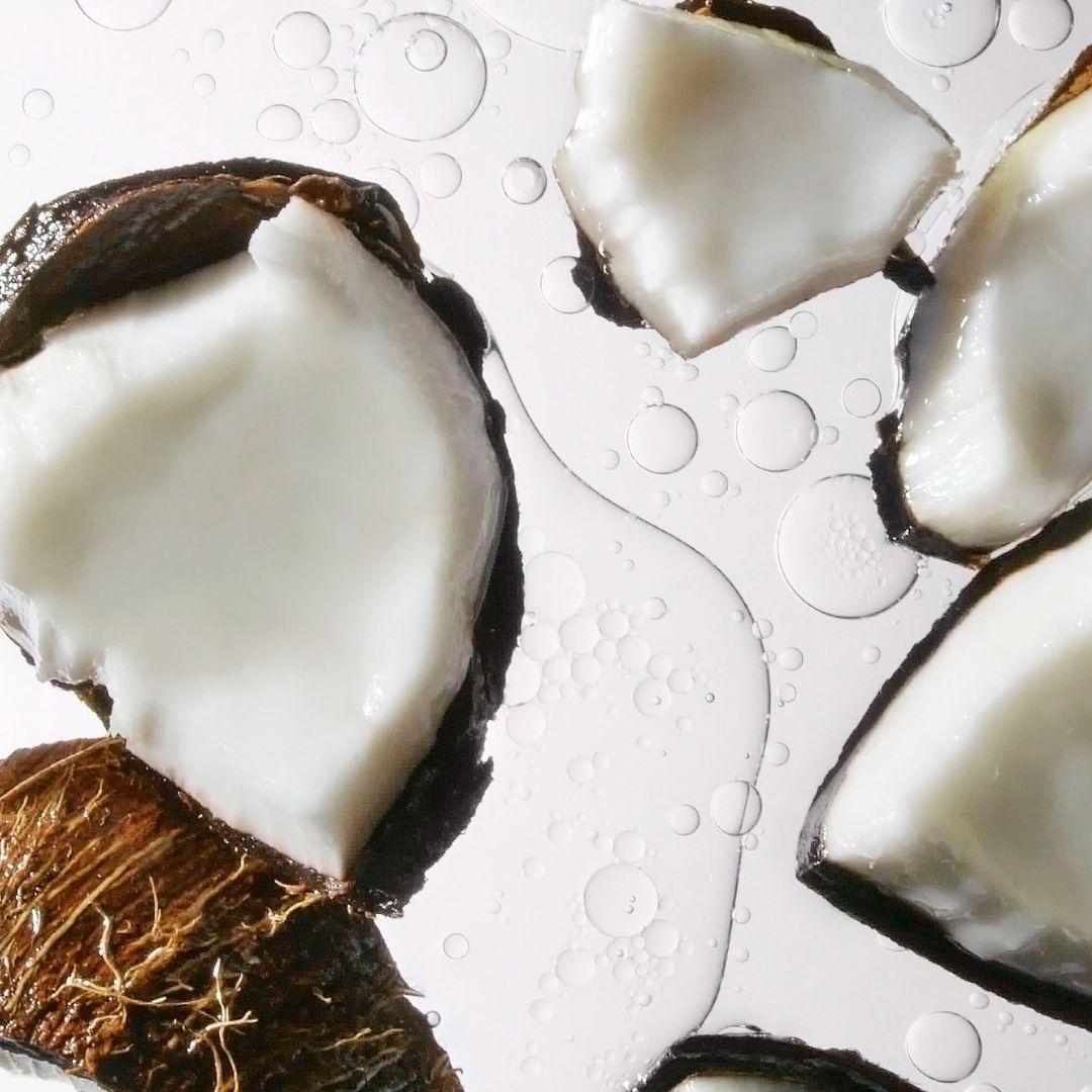 Close-up shot of coconut pieces on a white surface with water droplets. Food and beverage photography showcasing coconut texture.