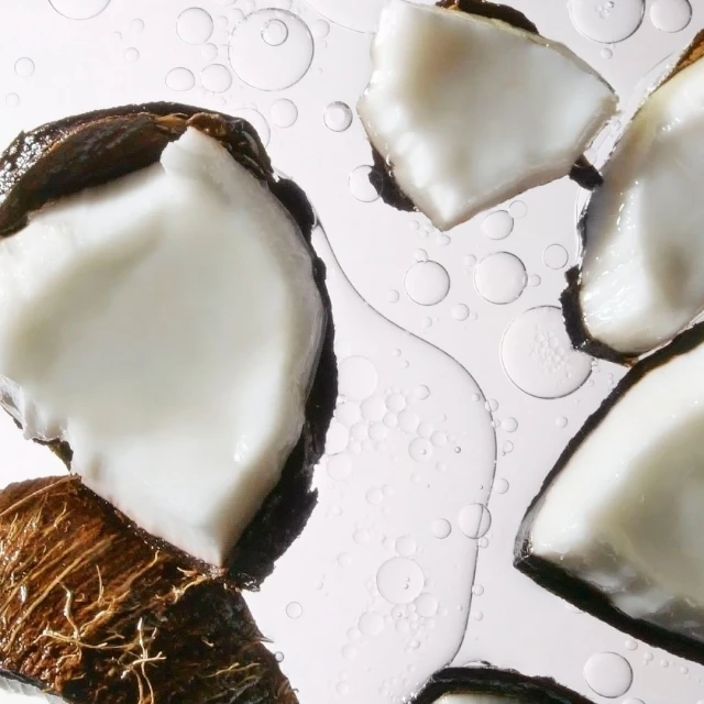 Close-up shot of coconut pieces on a white surface with water droplets. Food and beverage photography showcasing coconut texture.