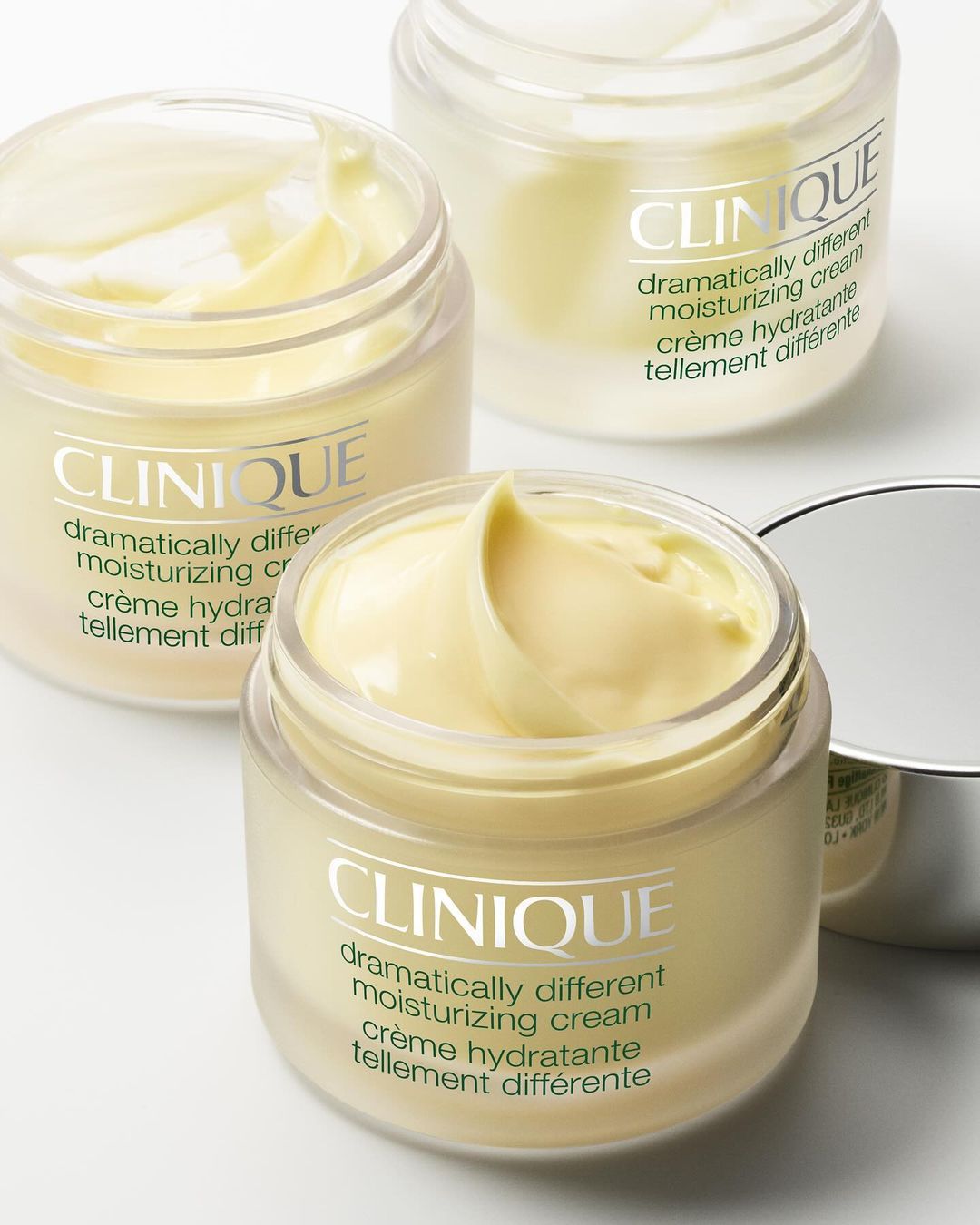 Three jars of Clinique Dramatically Different moisturizing cream with their product names visible. Beauty and skincare product shot.