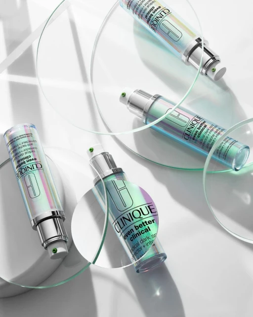 Clinique 'Even Better Clinical' serum bottles arranged with transparent circular stands on a white background in a beauty product shot.